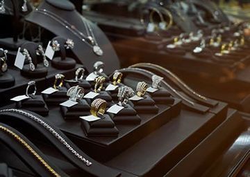 Exhibición de anillos de plata y oro sobre bandejas de terciopelo negro en una joyería.