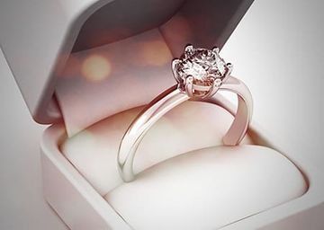 Anillo con gema en forma de corazón en un joyero blanco con iluminación rosa suave.
