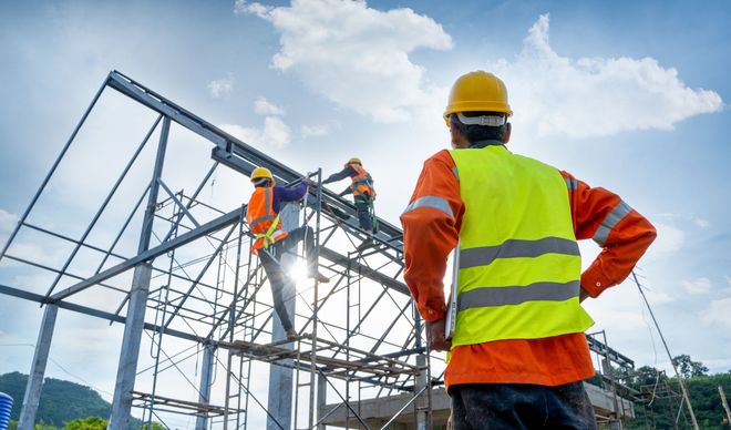 Ein Bauarbeiter steht auf einer Baustelle und schaut in die Ferne