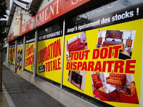Affiche indiquant une liquidation posée sur une vitrine qui donne dans la rue.