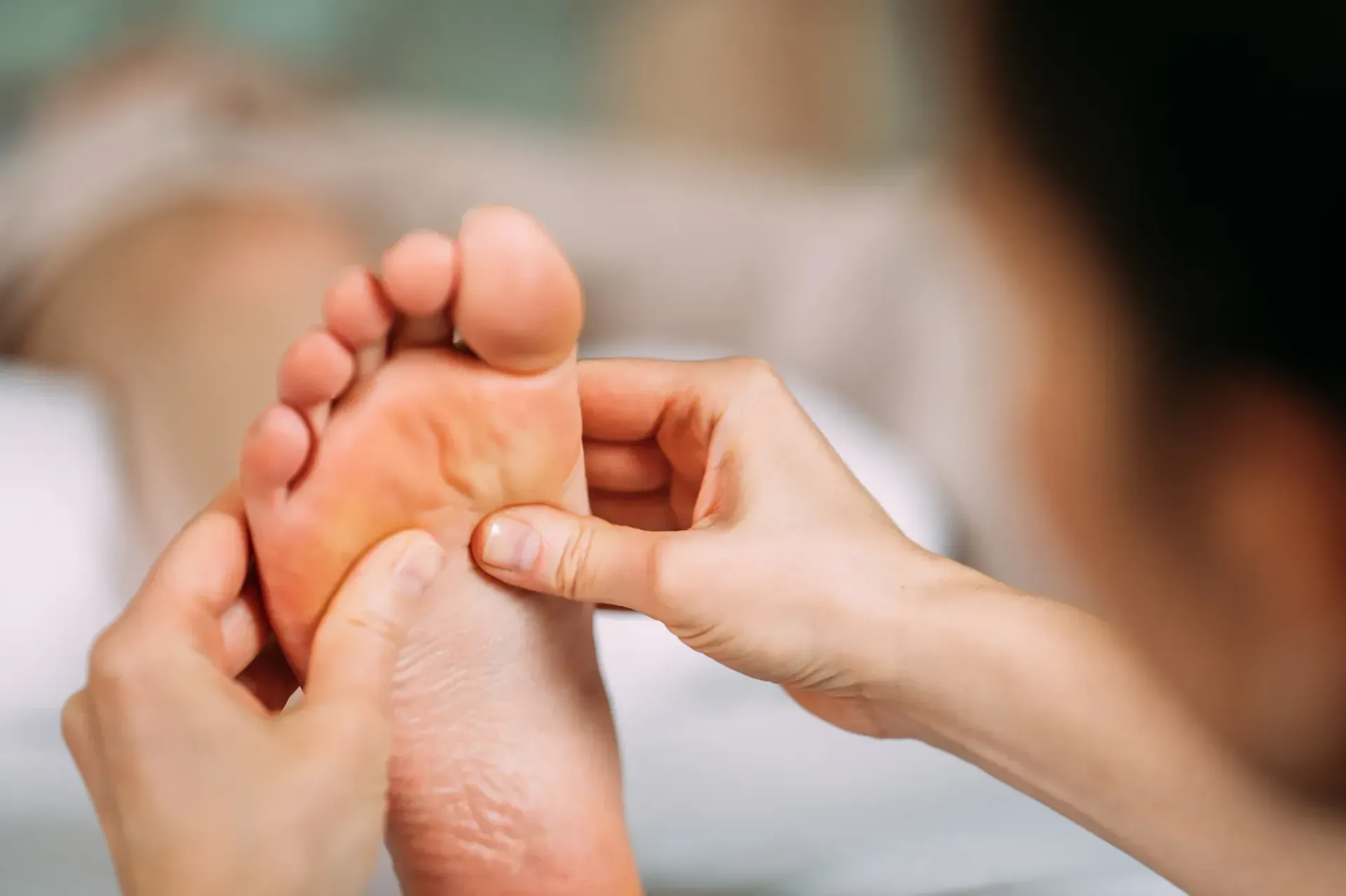 Eine Person bekommt von einem Masseur eine Fußmassage.