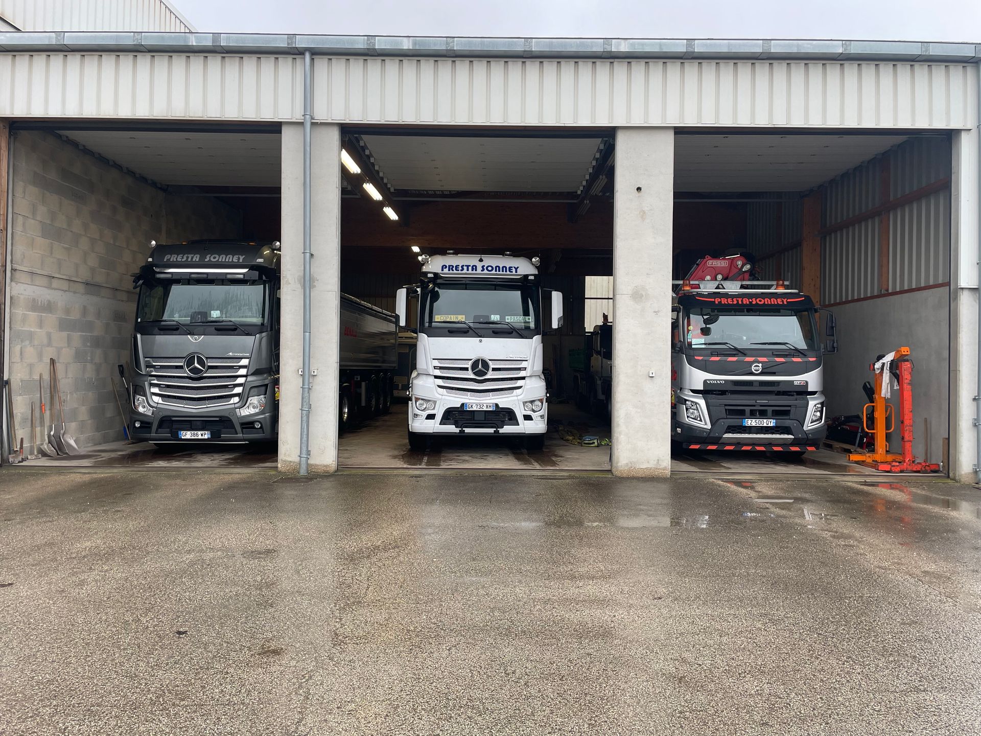 Photo de trois camions-bennes dans un garage