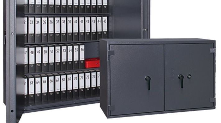 Dos armarios metálicos de color gris oscuro. El más grande está abierto y contiene filas de cajas negras etiquetadas.