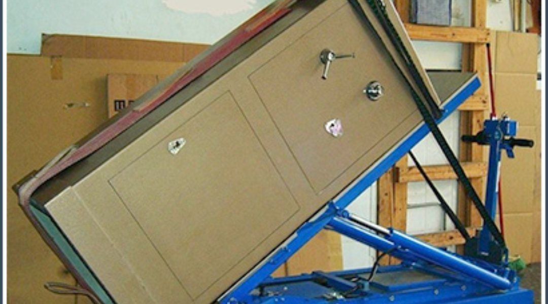 Una gran caja de cartón siendo levantada por una máquina azul en un almacén.