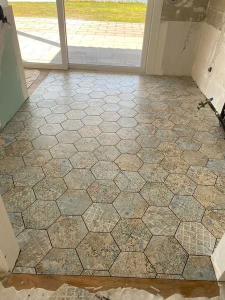 Sol carrelé hexagonal dans une pièce, déclinant différentes nuances de bleu et de beige.