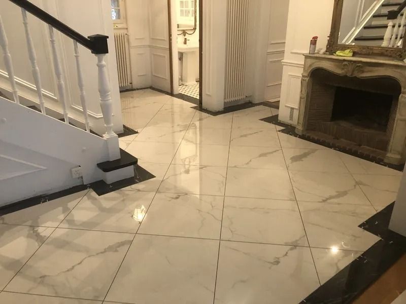 Hall d'entrée carrelé en marbre blanc brillant avec un escalier, une cheminée et une porte menant à une salle de bain.