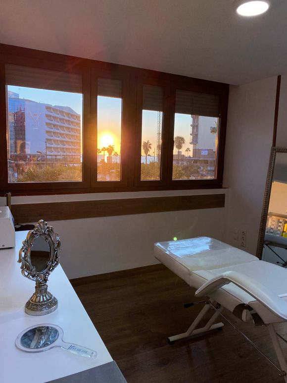 Una habitación con una cama y un espejo con el sol brillando a través de las ventanas.