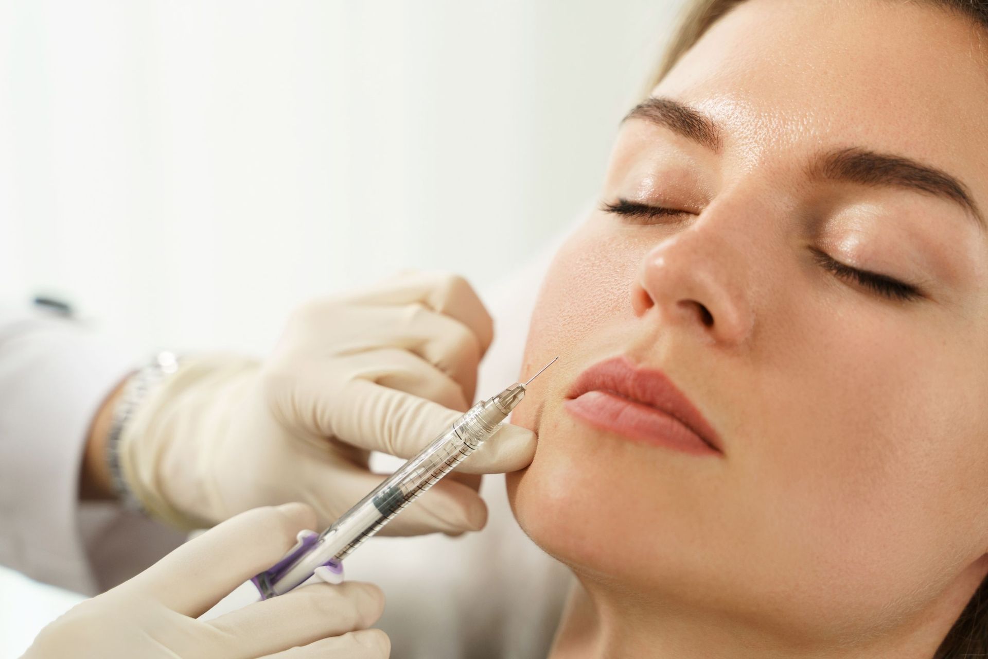 Una mujer recibe una inyección de botox en los labios.