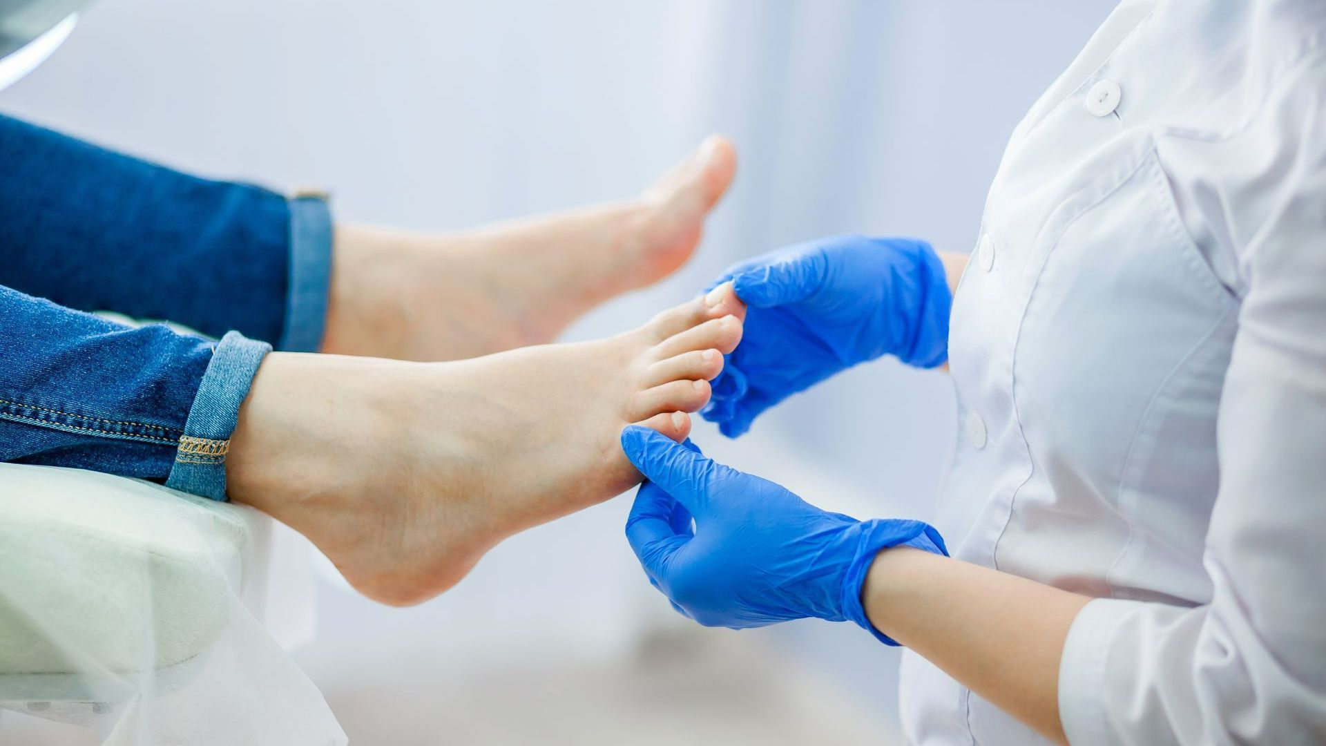 Une soignante gantée de bleu tient le pied d'un patient