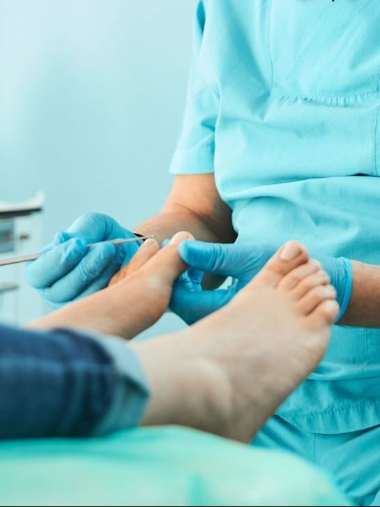 Un médecin en blouse et gants traite le pied d'un patient