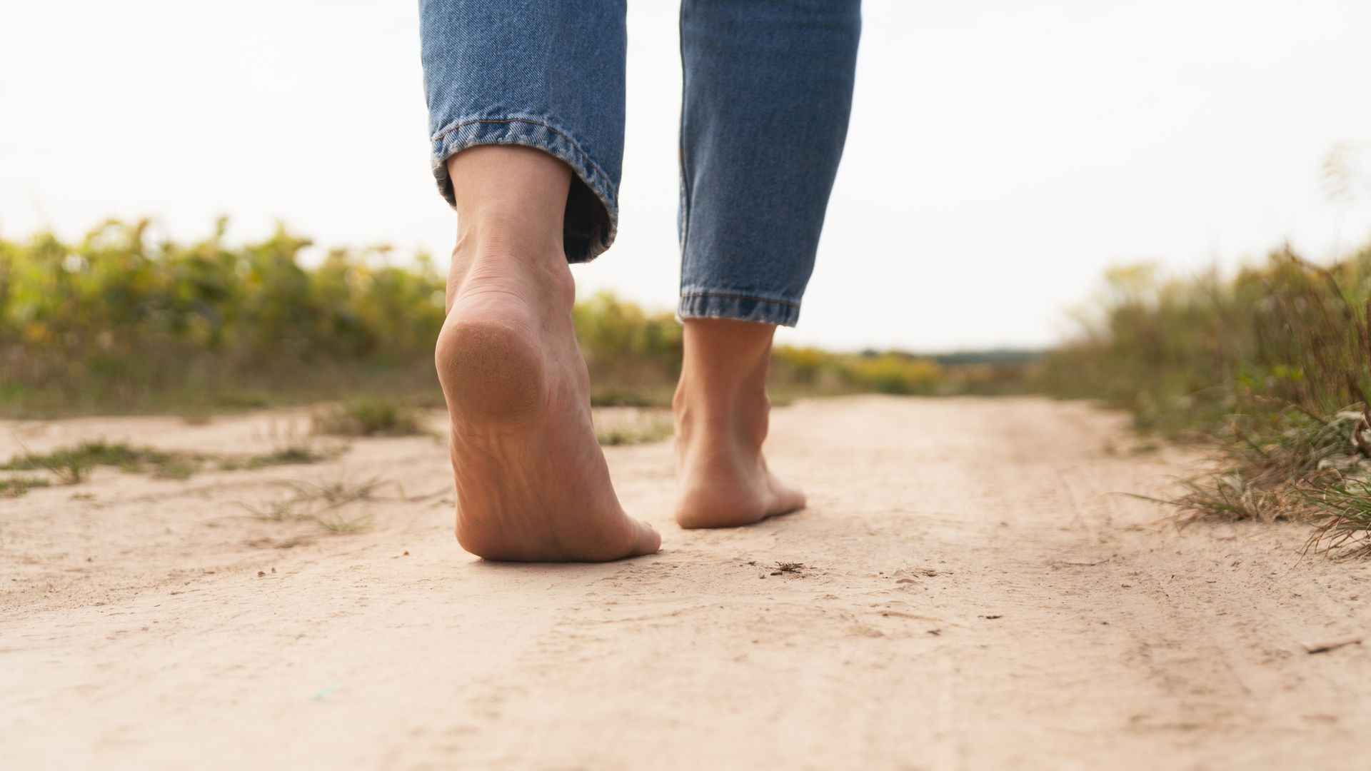 Une personne avec des pieds nus marche sur du sable