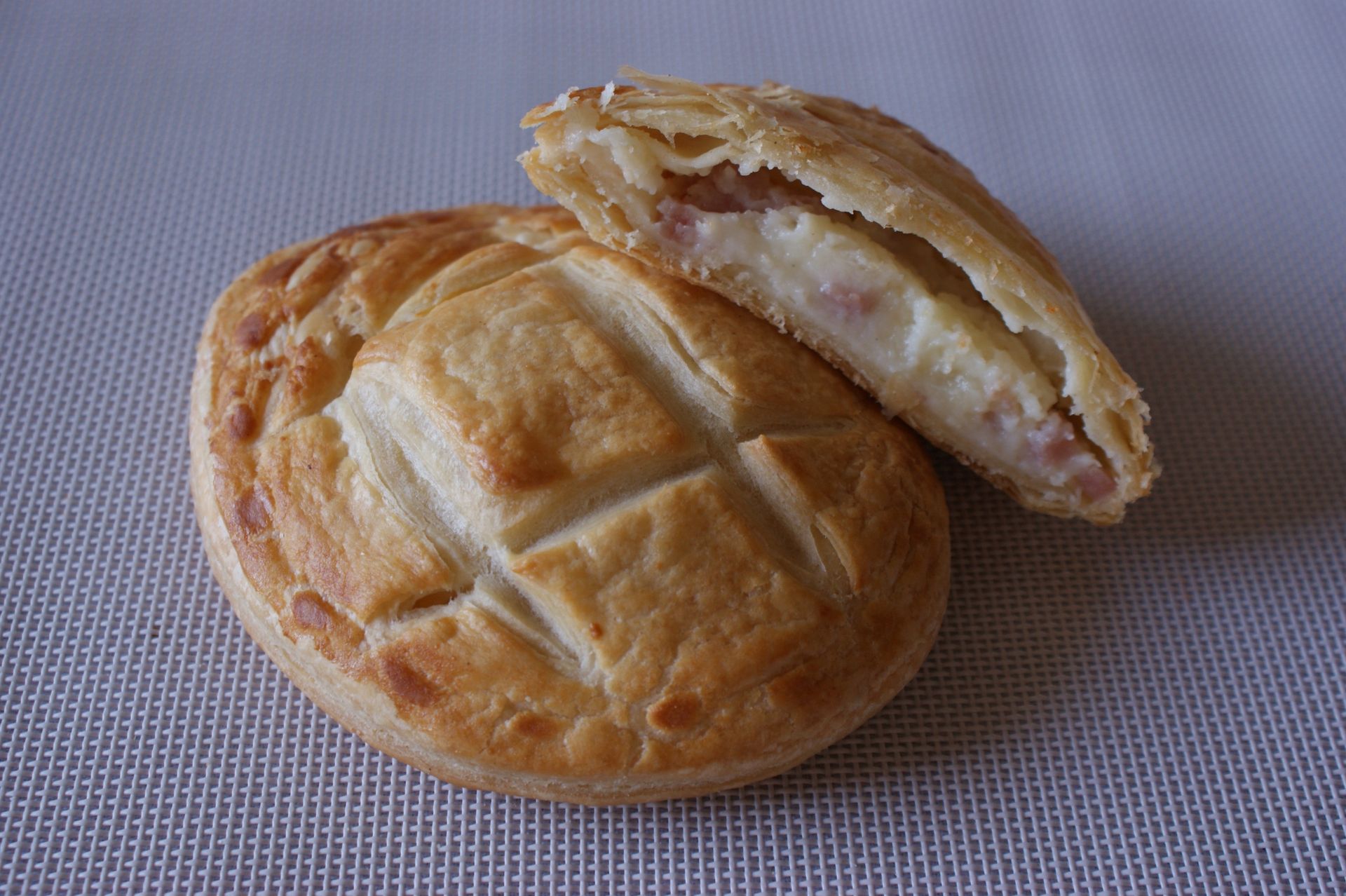 Un pastel con jamón y queso se corta por la mitad sobre una mesa.