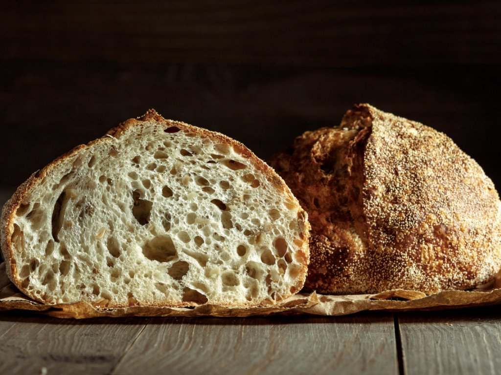 Una hogaza de pan se corta por la mitad sobre una mesa de madera.
