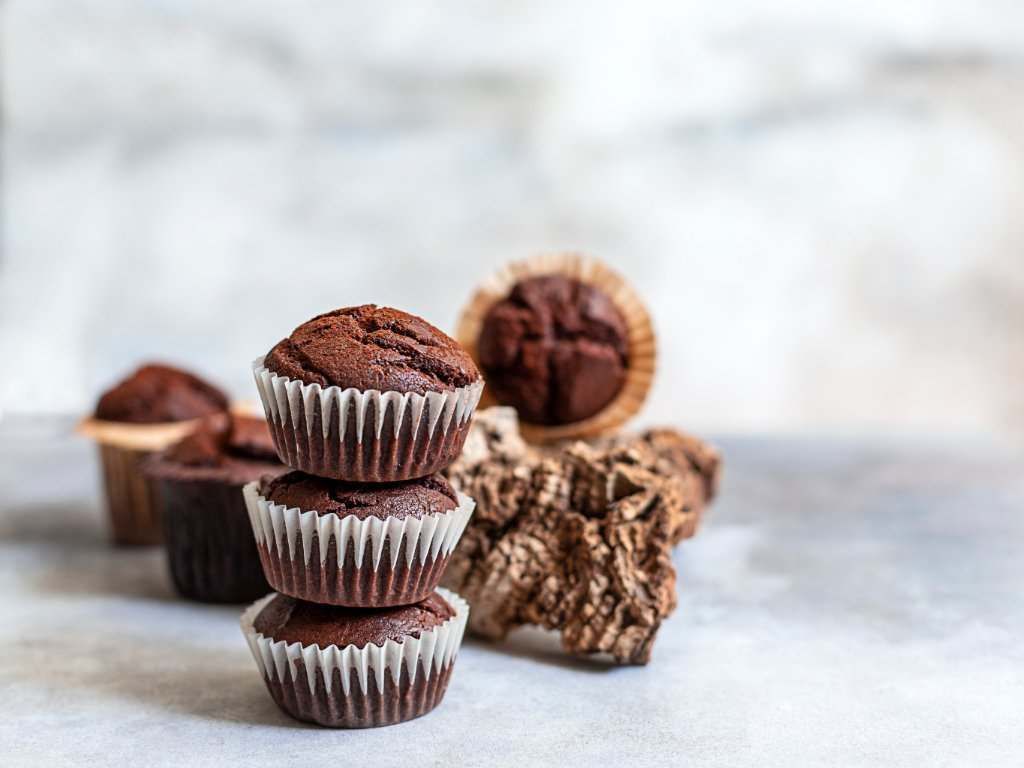 Tres muffins de chocolate están apilados uno encima del otro sobre una mesa.