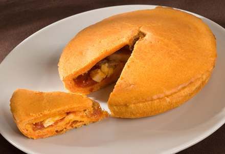 En un plato blanco hay un pastel del que se ha sacado una rebanada.