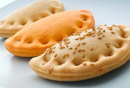 Tres pasteles con semillas de sésamo encima están en un plato blanco.