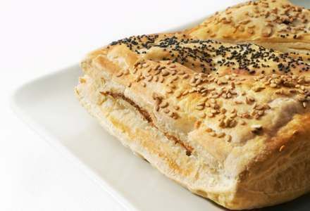 Un trozo de pan con semillas de sésamo encima está en un plato blanco.