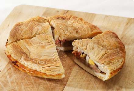 Un pastel del que se ha sacado una rebanada está sobre una tabla de cortar de madera.