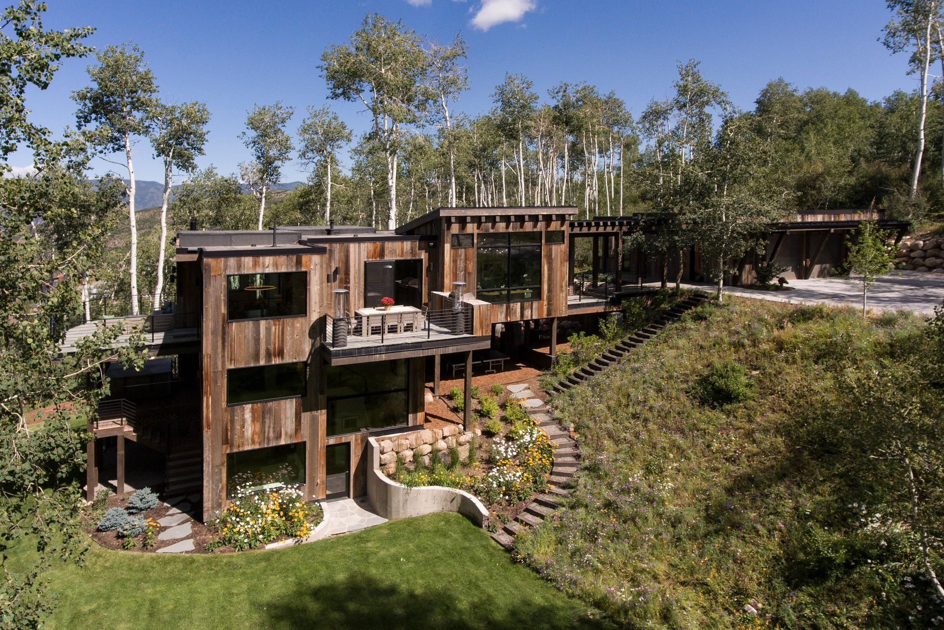 A large wooden house sits on top of a hill surrounded by trees