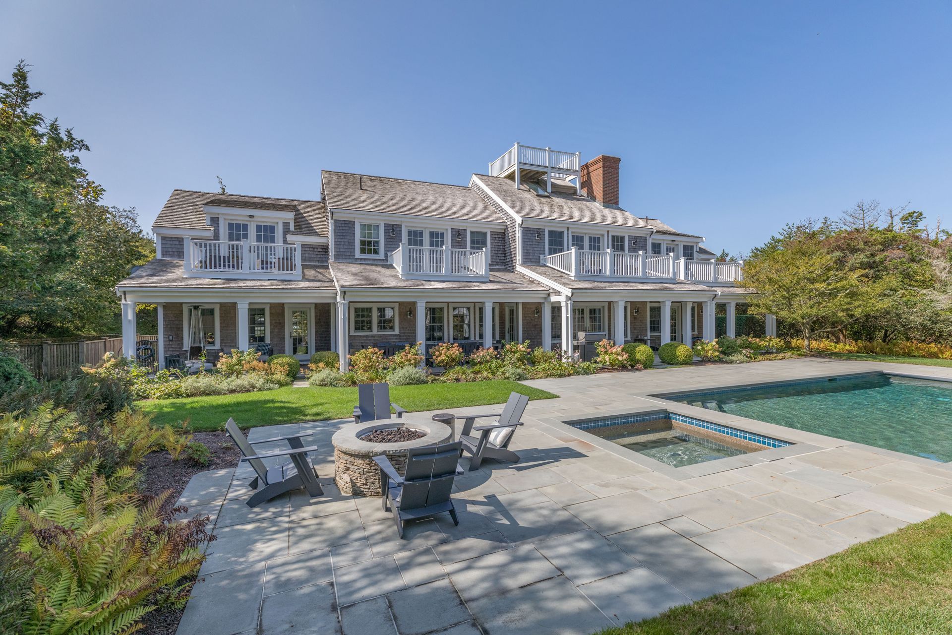 A large house with a swimming pool and a fire pit in front of it.