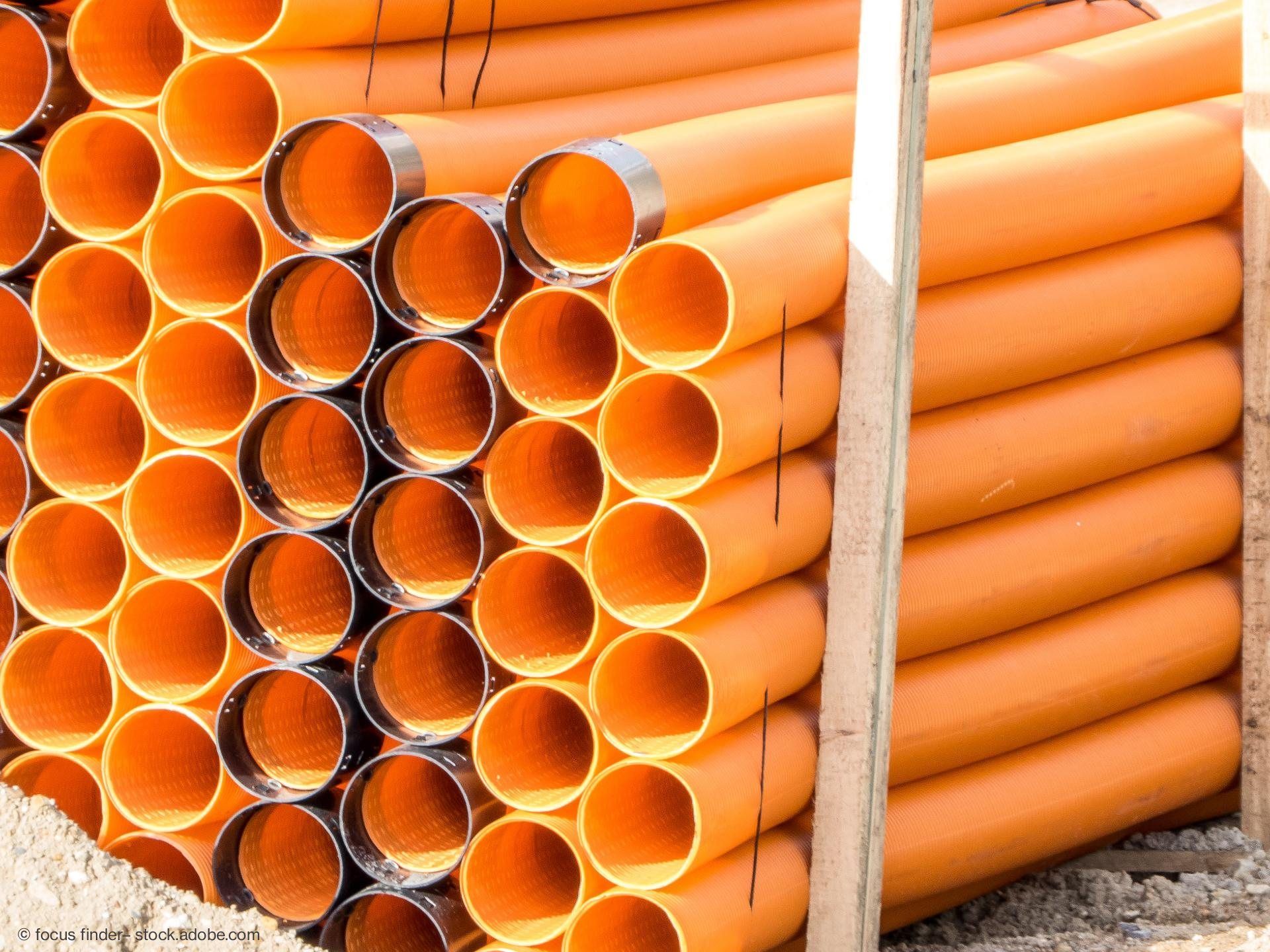 Orangene PVC-Rohre gestapelt – Baumaterial für Tiefbau und Entwässerung