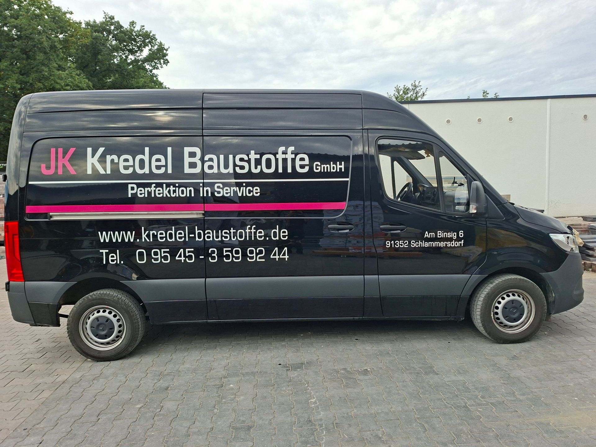 Firmenbus der JK Kredel Baustoffe mit Fahrzeugbeschriftung, seitliche Ansicht