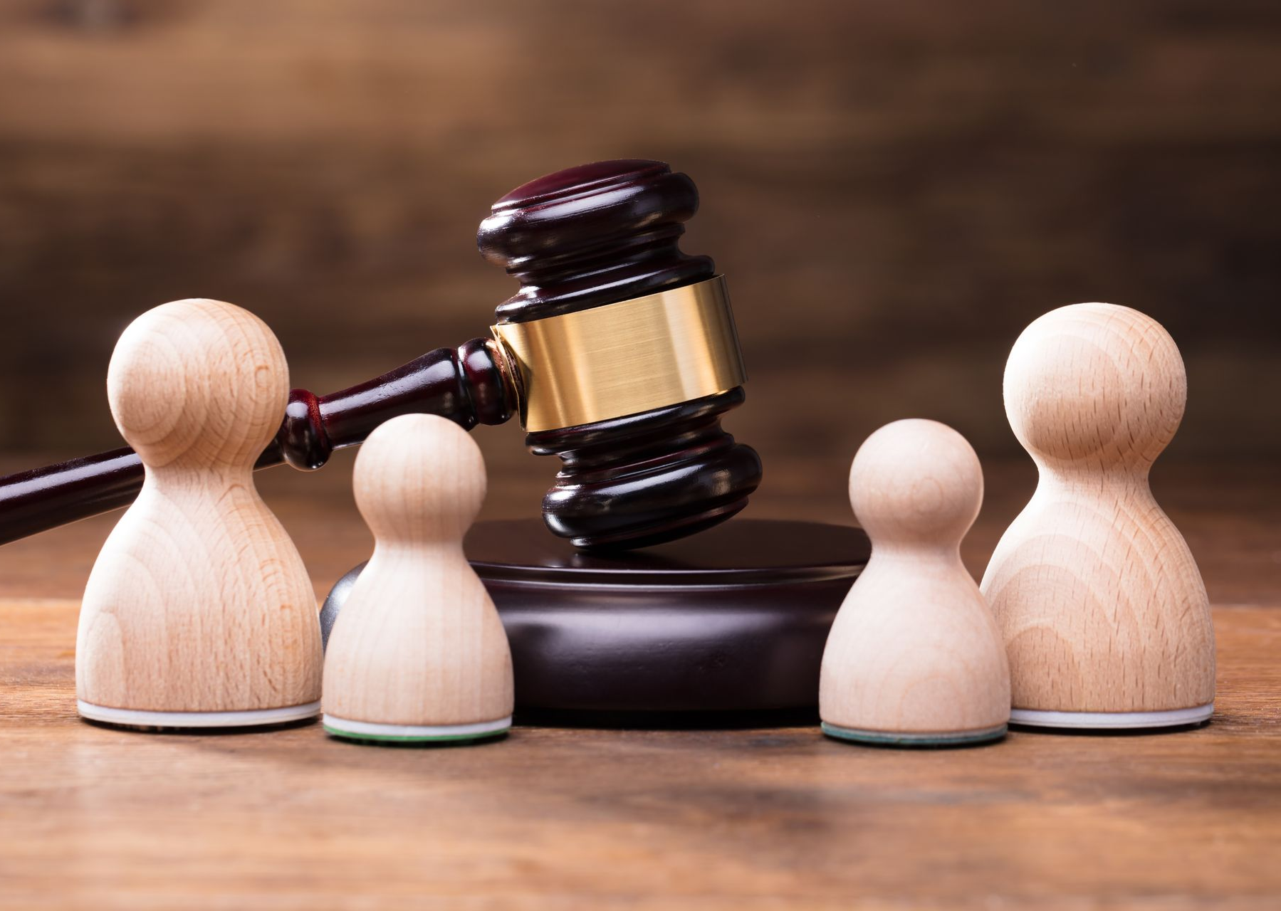 Figuras de madera bajo un mazo, simbolizando una decisión legal sobre la familia.