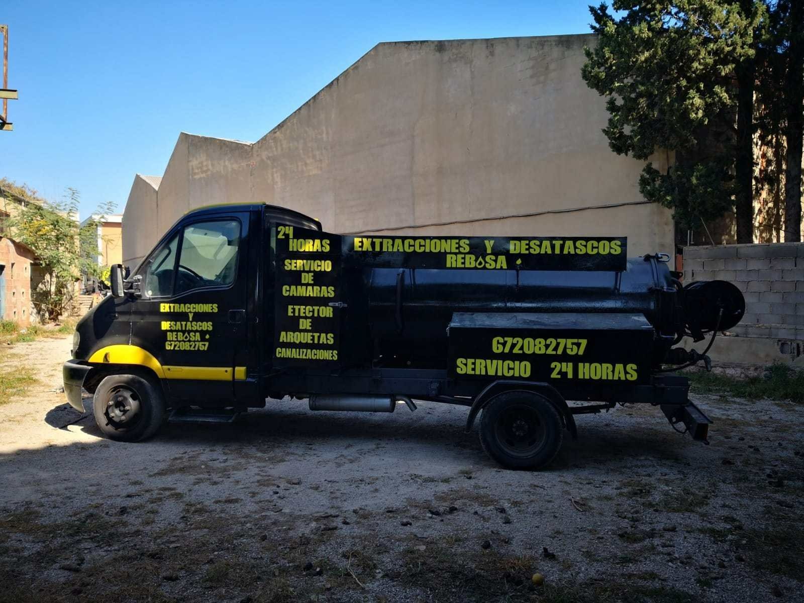 Un camión negro y amarillo está estacionado frente a un edificio.