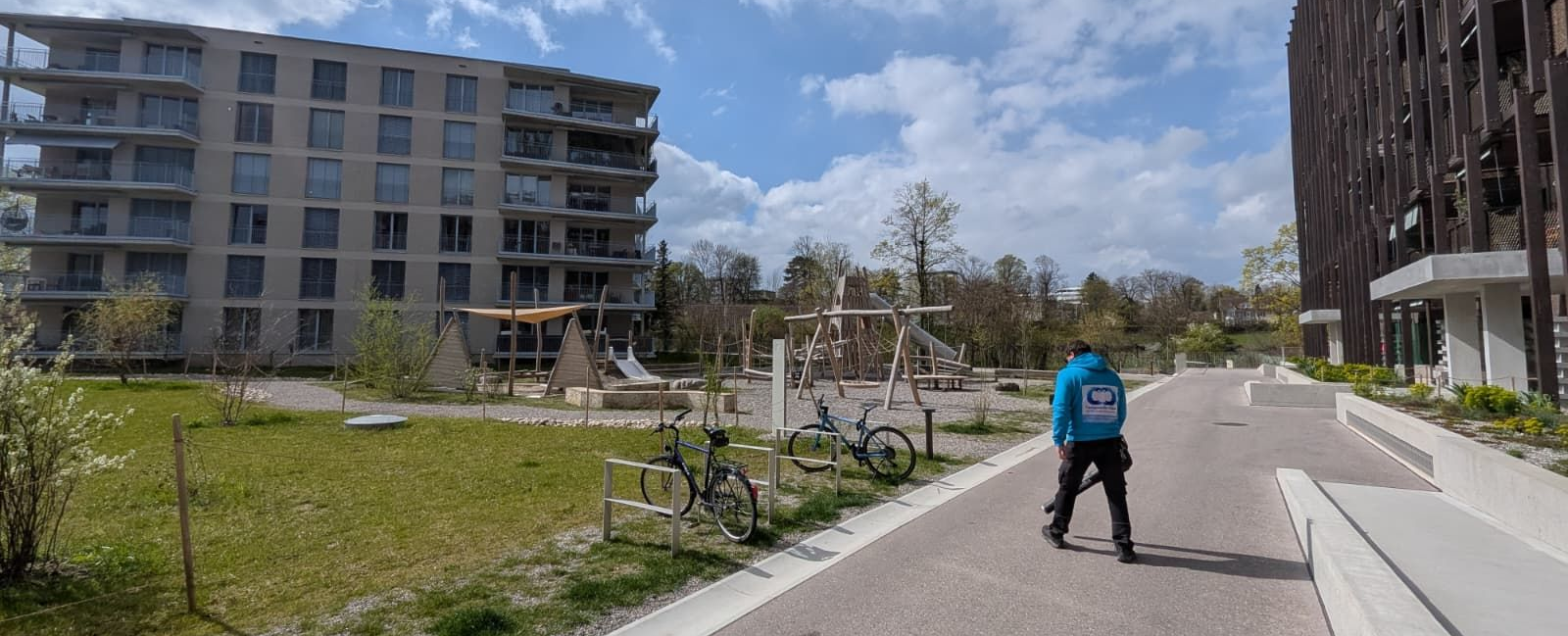 Eine Person in grauer Uniform wischt einen dunklen Fliesenboden in einem Innenraum mit Treppenhaus.