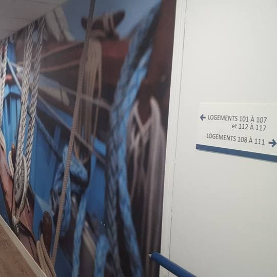 Toile tendue imprimée dans un couloir, avec un panneau indiquant des numéros de logement.
