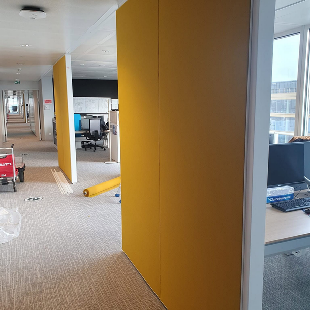 Intérieur de bureau avec panneaux muraux jaunes, bureaux et chaises.