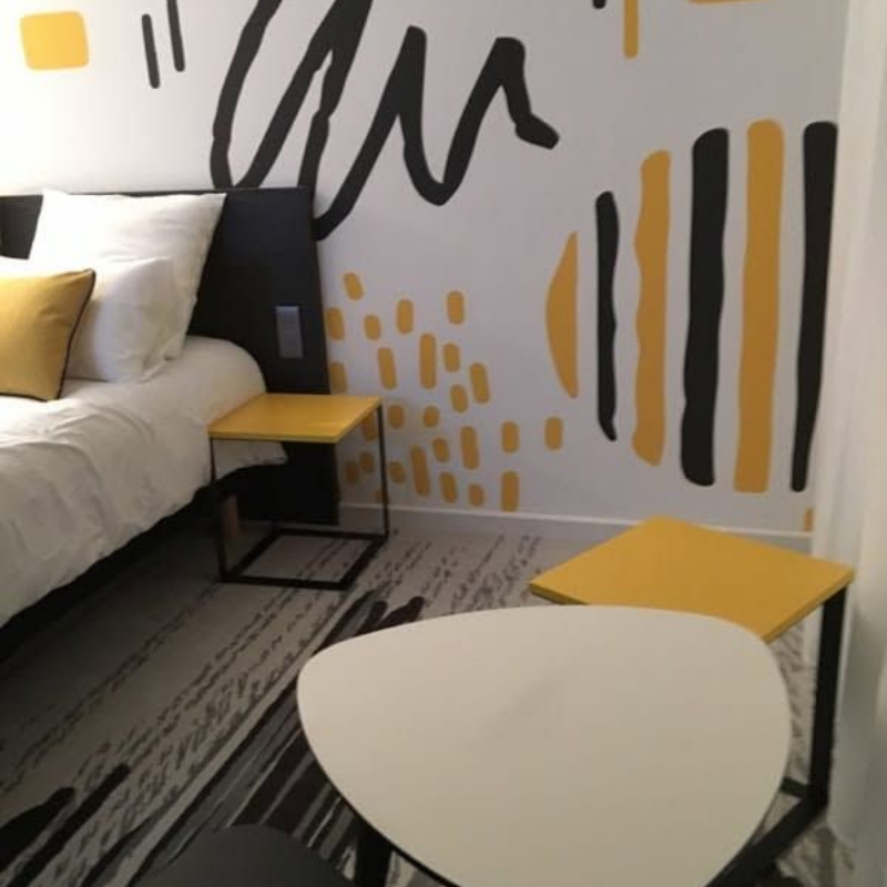 Chambre moderne avec un mur en toile tendu imprimée ; motifs graphiques noirs et jaunes.