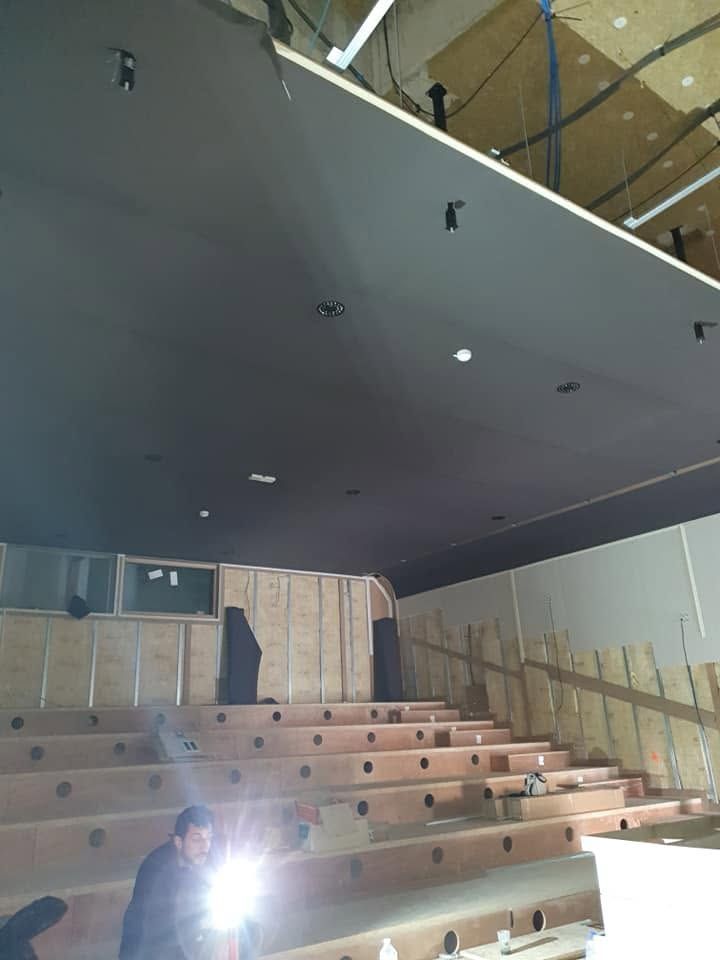 Vaste plafond acoustique en toile tendue au-dessus des gradins d'une salle.