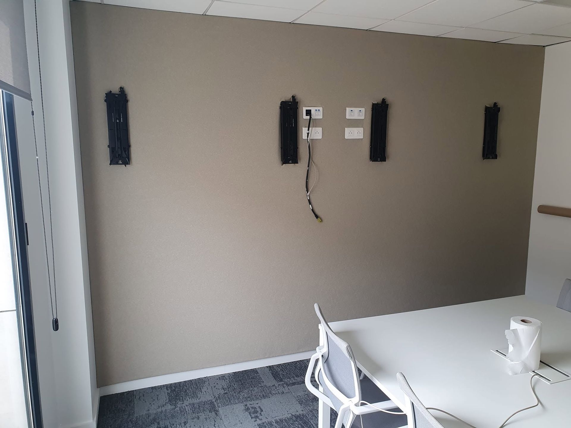 Mur en tissu tendu dans une salle de réunion avec une table et une chaise blanches au premier plan.