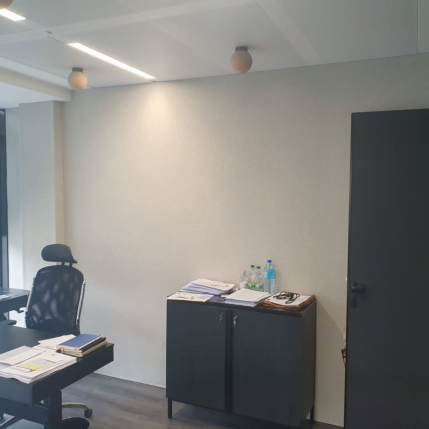 Intérieur de bureau moderne avec un bureau, une chaise, une armoire et un mur en toile tendu.