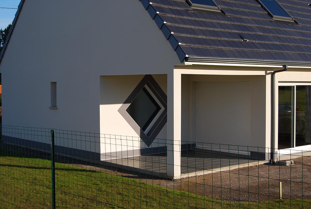 Terrasse carrelée abritée par une extension du toit en ardoise de la maison