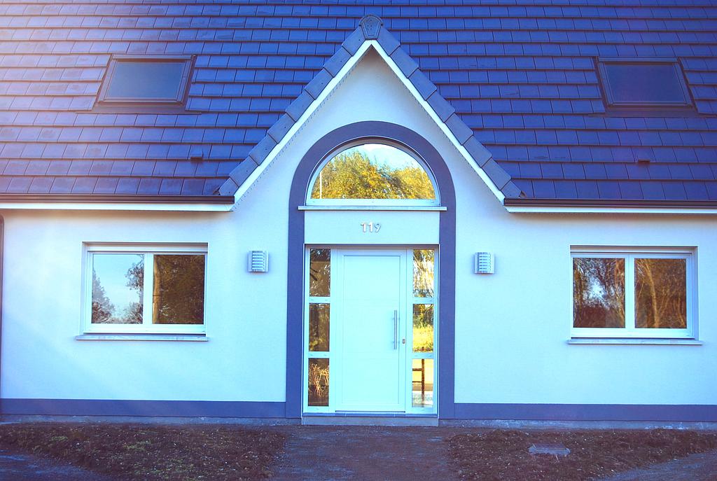 Zoom sur la porte d'entrée en PVC entourée de vitrage de la maison numéroté 119