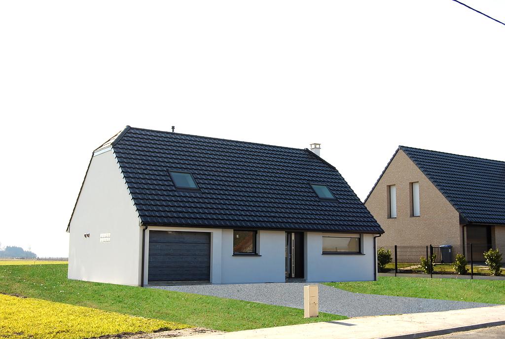 Maison individuelle aux façades blanches équipée d'une porte de garage sectionnelle en bois peint en noir