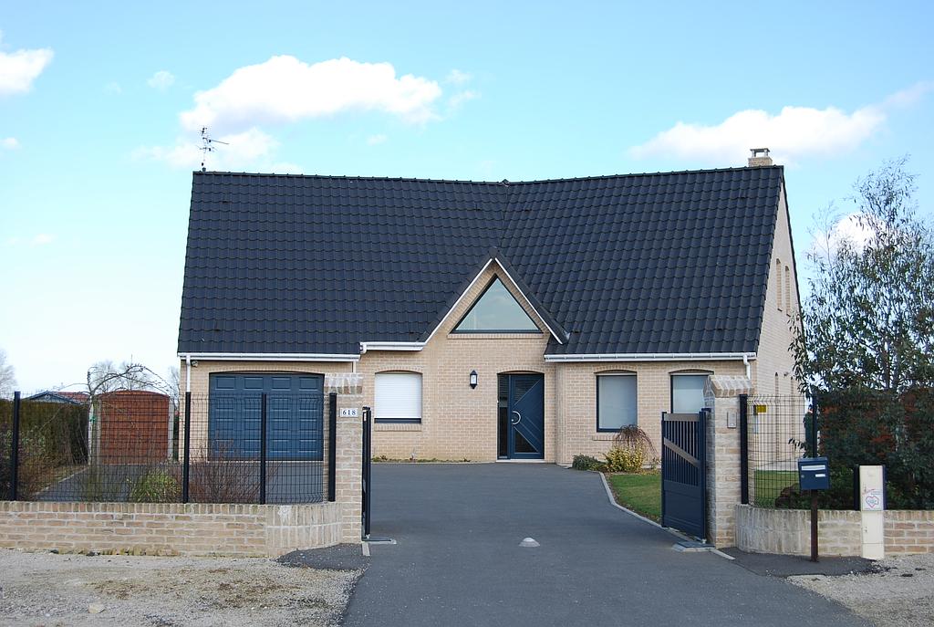 Maison individuelle avec porte semi-vitrée en aluminium surmontée d'une fenêtre triangulaire