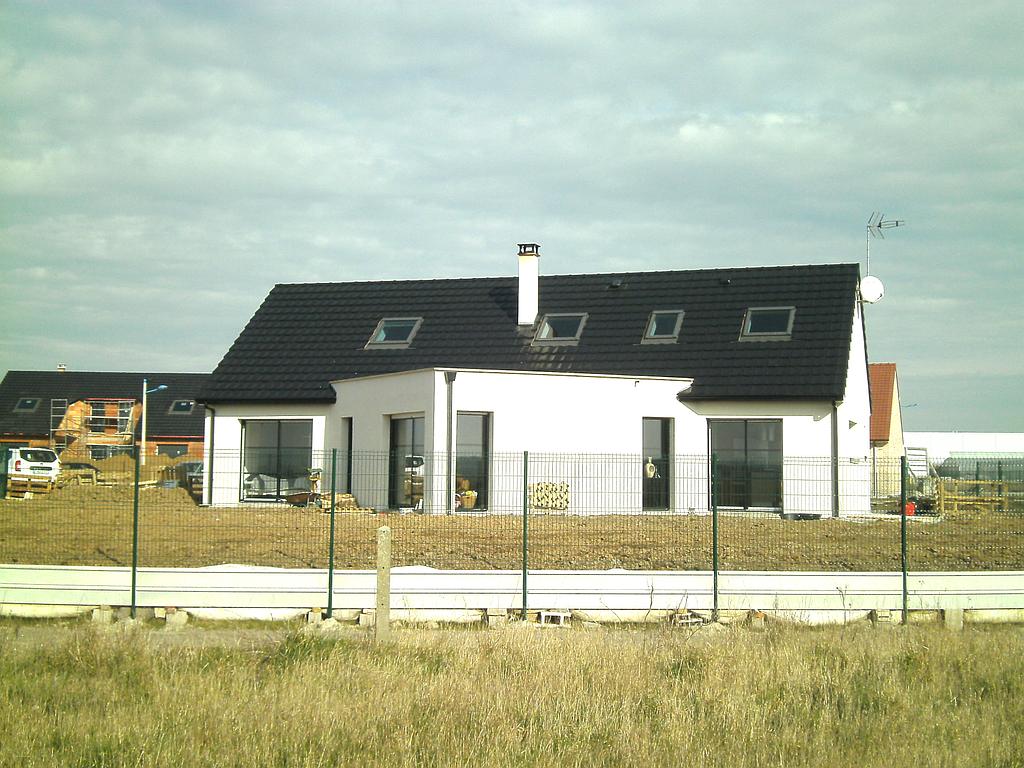 Maison individuelle dont le terrain n'est pas encore aménagé, la pièce de vie forme un angle donnant vers l'extérieur