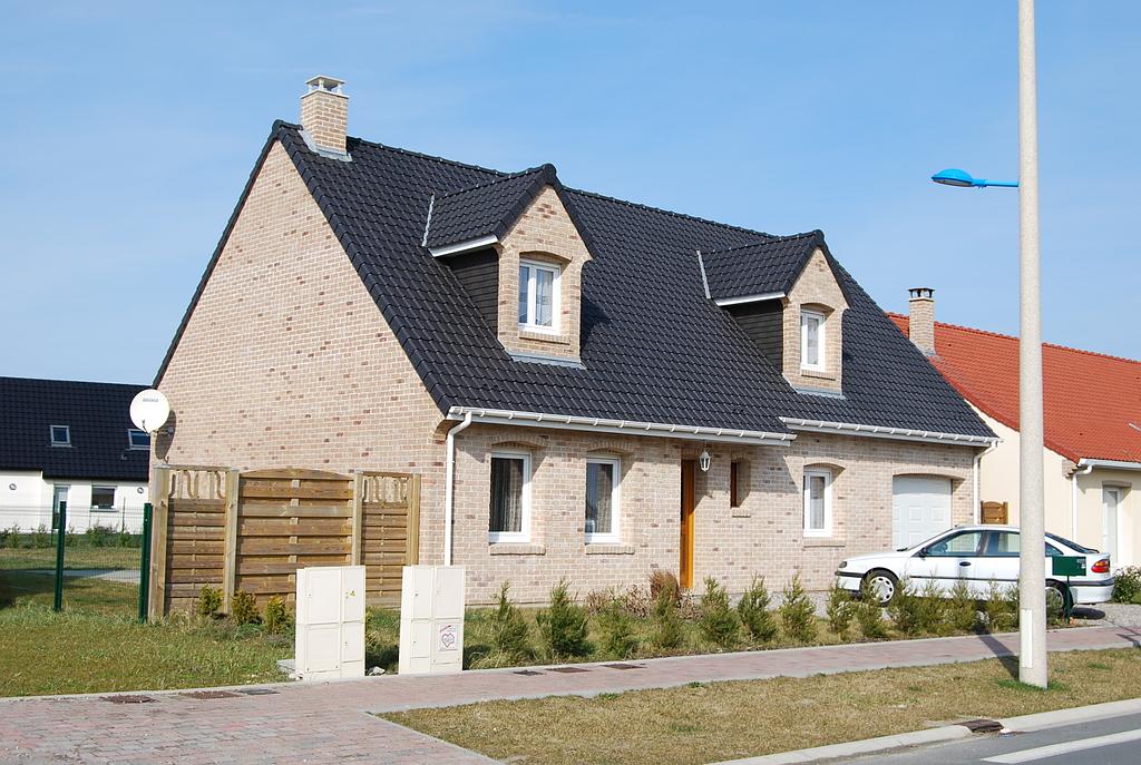 Une maison individuelle avec un toit noir située dans un lotissement