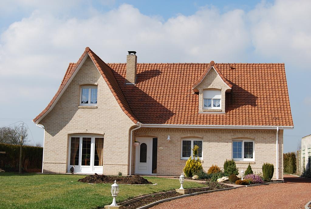 Maison individuelle classique avec terrain avant aménagé et chemin pour la voiture en gravier rouge