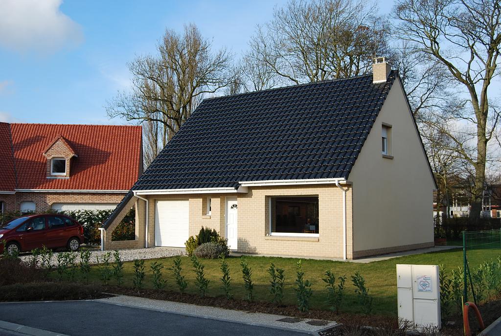 Maison individuelle de petite taille. Le toit possède une prolongation jusqu'au sol du côté du garage