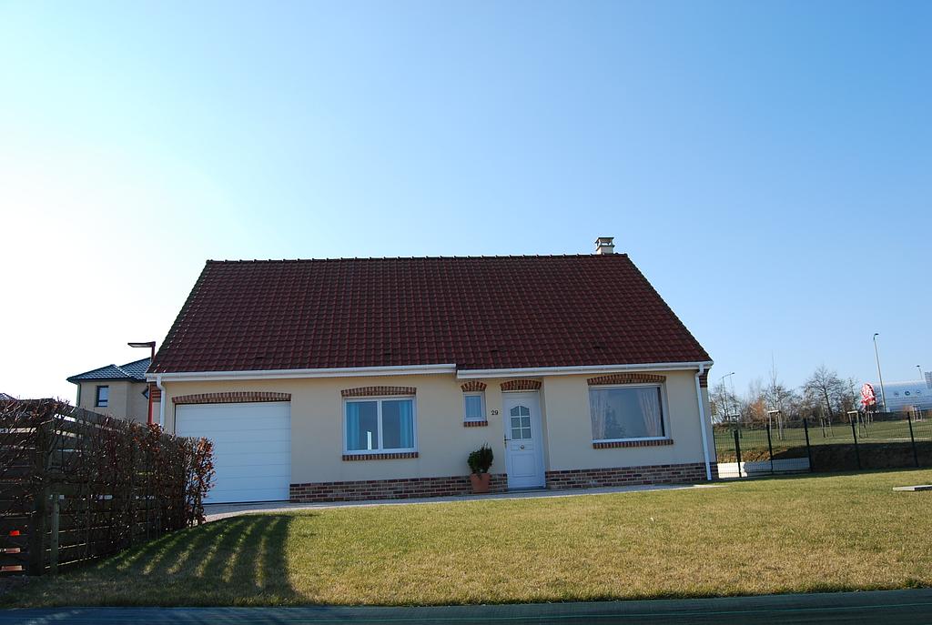 Maison individuelle en crépis et briques rouges dont les menuiseries extérieures sont toutes en PVC