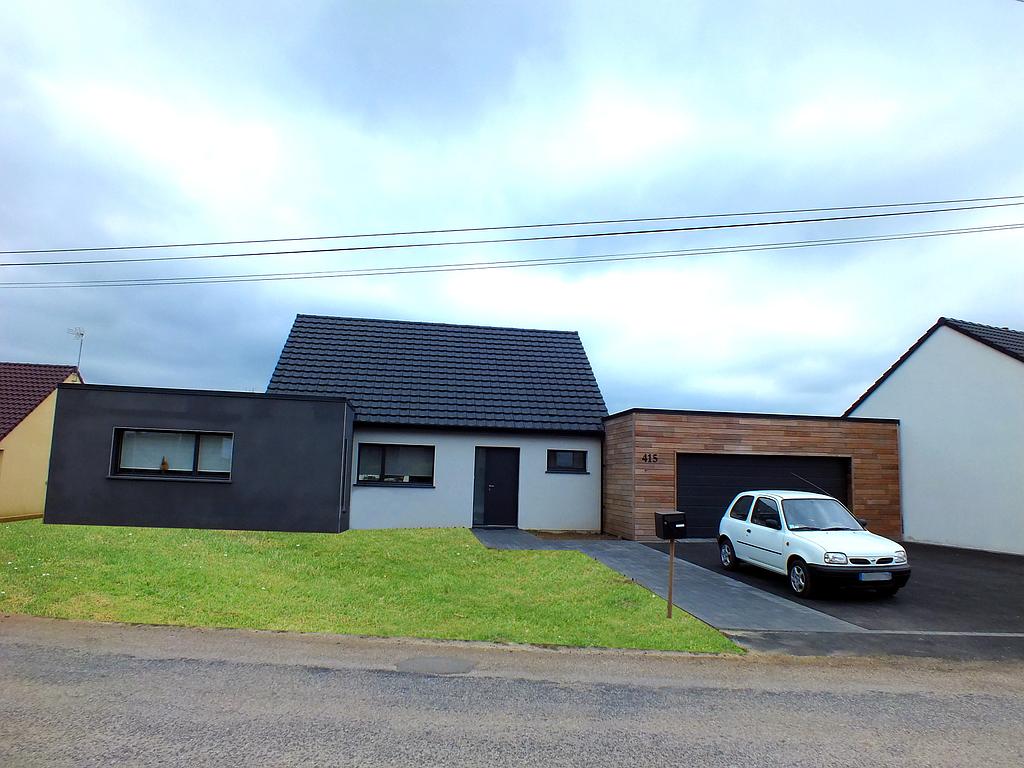 Maison neuve individuelle en trois teintes différentes :  blanche au milieu, noire à gauche et avec un garage en lames de bois
