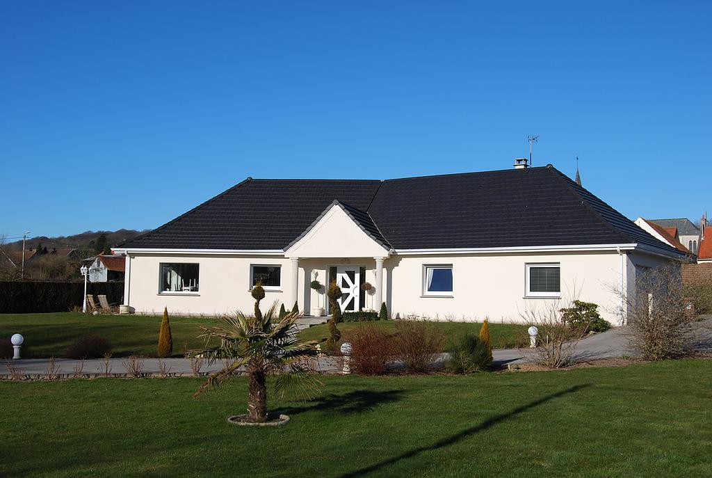 Maison de plain-pied à la façade blanche sur un grand terrain récemment arborée