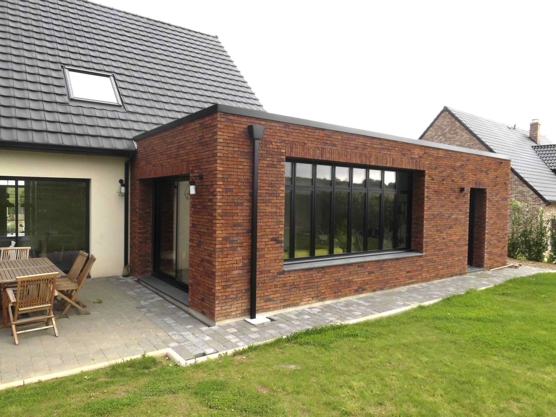 Extension de maison en brique rouge avec une grande baie vitrée