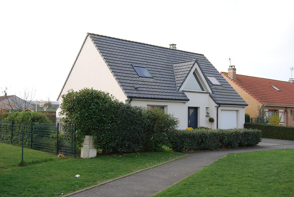 Maison individuelle moderne dont le terrain est délimité par des buissons