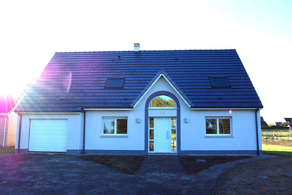 Photo prise en contrejour d'une maison individuelle avec menuiseries PVC et fenêtre Velux