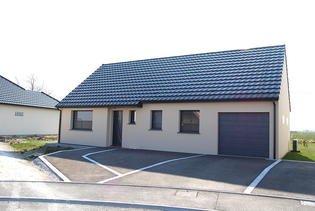 Maison individuelle reculée par rapport à la route dont les menuiseries extérieures et le toit sont de couleur noire